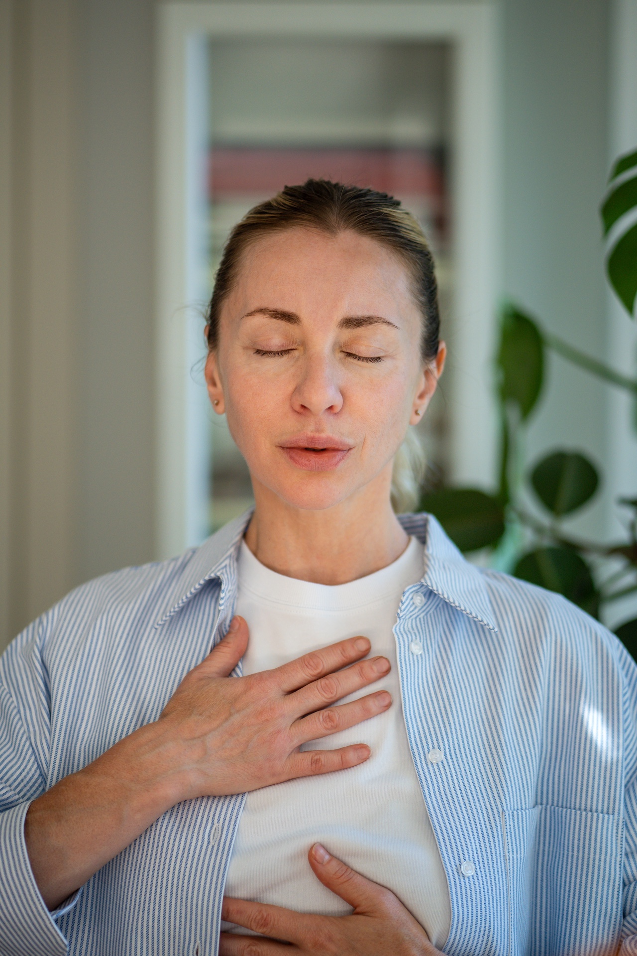 Person meditiert mit geschlossenen Augen und einer Hand auf der Brust.