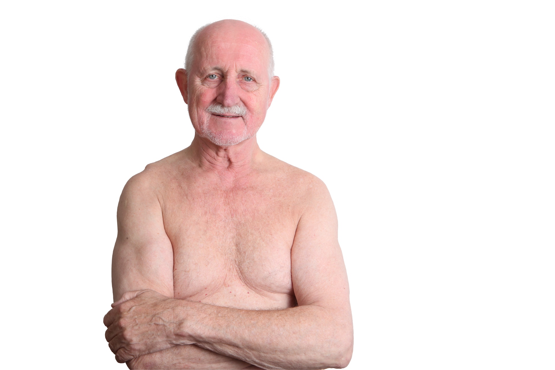 Ein älterer Mann mit freiem Oberkörper lächelt vor einem weißen Hintergrund.