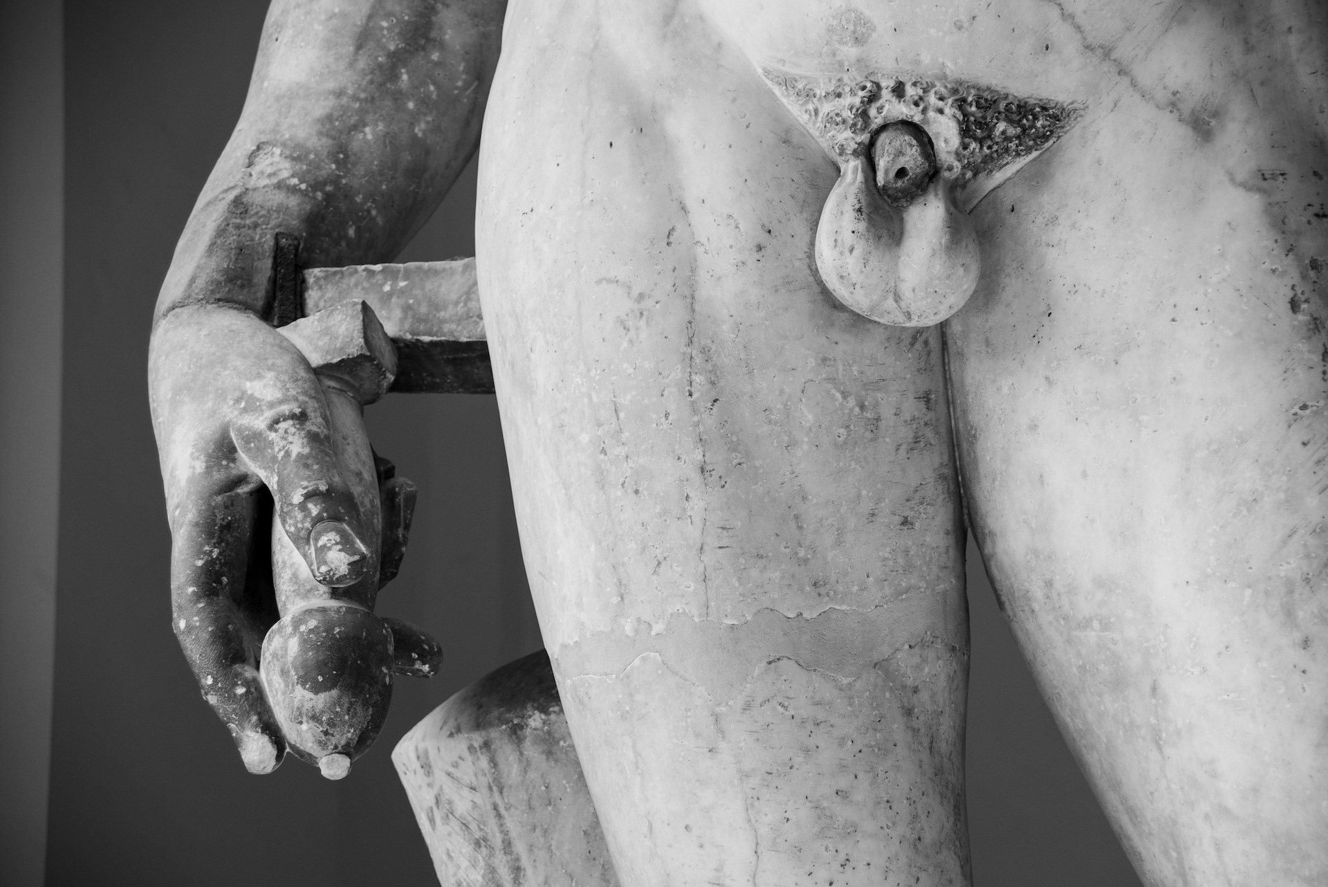 Eine antike Skulptur mit Fokus auf die Torso- und Handdetails.